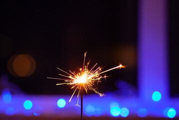 Sparks and fire on a black and blue background. Festive Merry Christmas sparklers. Golden Magic...
