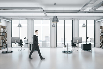 Businessman walking in office interior with computers