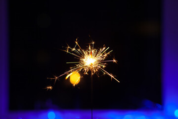 Sparks and fire on a black and blue background. Festive Merry Christmas sparklers. Golden Magic...