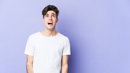 Young caucasian man isolated on purple background shouting very angry, rage concept, frustrated.