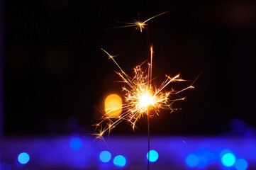 Sparks and fire on a black and blue background. Festive Merry Christmas sparklers. Golden Magic...