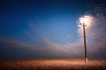 the moon over the field with power lines