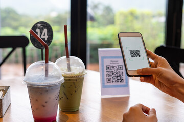 Women's hands are using  the phone to scan the qr code to select food menu. Scan to get discounts or pay for food. The concept of using a phone to transfer money or paying money online without cash.