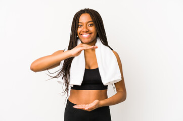 Young african american sport woman isolated holding something with both hands, product presentation.