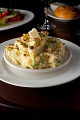 Steakhouse side dishes. Asparagus, salad, tomatoes, mashed potatoes, red onions, cream cauliflower, pickled peppers, seasoned meats served in cast iron skillet. Traditional appetizer items.