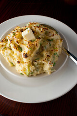 Potatoes au gratin. Potatoes baked in butter, cheese cream sauce, garnished with scallions, parsley and served in cast iron skillet. Classic American restaurant or French bistro side dish.