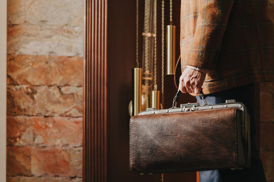 Man with valise stands in front of grandfather clock