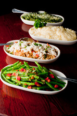 Steakhouse side dishes. Asparagus, salad, tomatoes, mashed potatoes, red onions, cream cauliflower, pickled peppers, seasoned meats served in cast iron skillet. Traditional appetizer items.