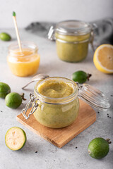 feijoa mashed with lemon and honey in glass jars on a light background