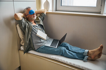 Elderly man giving eyes a break from working on laptop