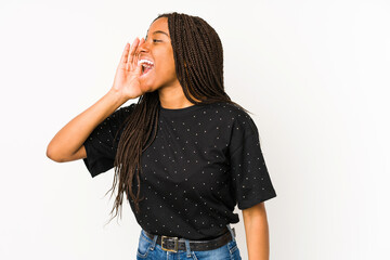 Young african american woman isolated on white background shouting and holding palm near opened...