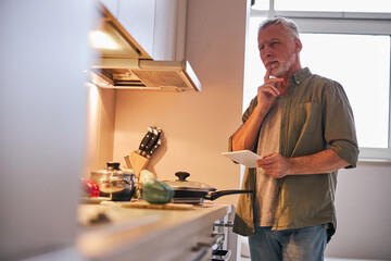 Elderly man at home considering ordering food delivery online