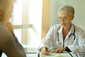 Obraz premium Mature woman doctor in medical consultation with patient