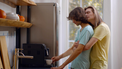 Fototapeta na wymiar Young gay couple at home in kitchen making fresh coffee
