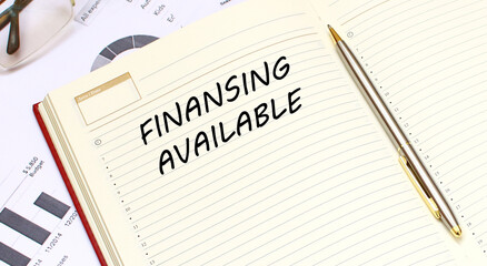 An open diary with text lies on an office desk with financial charts.