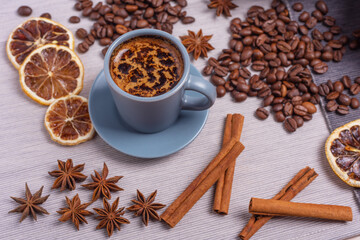 A cup of espresso is decorated with anise stars, cinnamon, sweets, dried lemons, acorns, peanuts in a beautiful dish.
