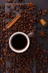 A cup of espresso is decorated with anise stars, cinnamon, sweets, dried lemons, acorns, peanuts in a beautiful dish.