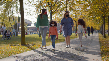 Mixed race family with homosexual parents wearing protective mask walking in autumn park