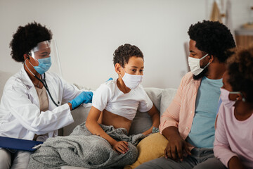 Obraz premium Doctor using a stethoscope listen to the lungs of little boy during examination at home