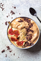 Chocolate smoothie bowl or vegan ice cream with figs and hemp seeds, gray background. Healthy vegan food concept.