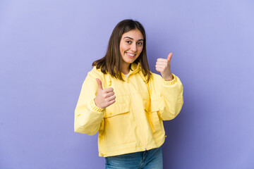 Young caucasian woman raising both thumbs up, smiling and confident.