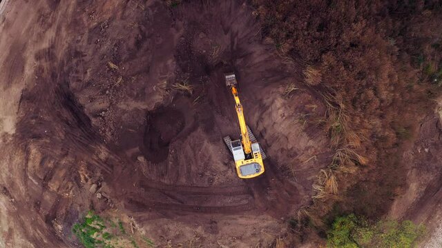 Crawler excavator working at the construction site. Construction machinery for excavating, loading, lifting and hauling of cargo on job sites. Aerial top view, 4K Video
