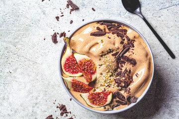 Chocolate smoothie bowl or vegan ice cream with figs and hemp seeds, gray background, copy space. Healthy vegan food concept.