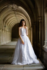 Beautiful girl wearing white wedding dress posing alone at a castle hall