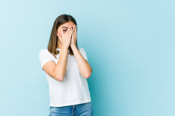 Young caucasian woman blink through fingers frightened and nervous.