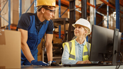 In Retail Warehouse Manager Uses Computer with Inventory Checking Software, Talks with Storehouse Worker about Package Delivery. International Distribution Center with Shelves Full of Products 