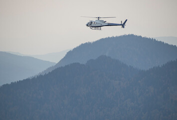 Fototapeta na wymiar Helicopter flying over mountains. Private copter. Emergency rescue service
