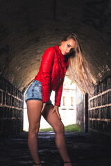 Sexy girl posing with a red jacket and short jeans in a ruined building.