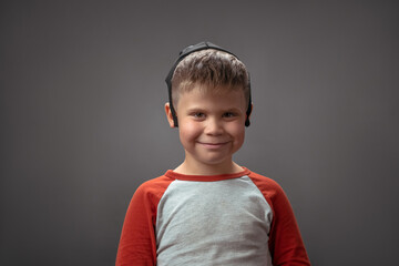Smiling Caucasian boy with face mask wearing at his head. Happy Little boy posing on grey background. High quality photo