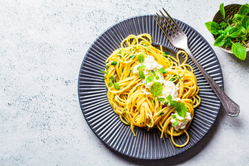 Pasta with ricotta and fresh basil in gray plate, top view.