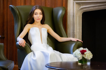 Portrait of a beautiful girl wearing white wedding dress sitting in the cabinet