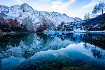 Reflections of snow capped mountains in a blue icy lake in the mountains