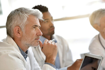 Portrait of mature doctor during meeting with medical team