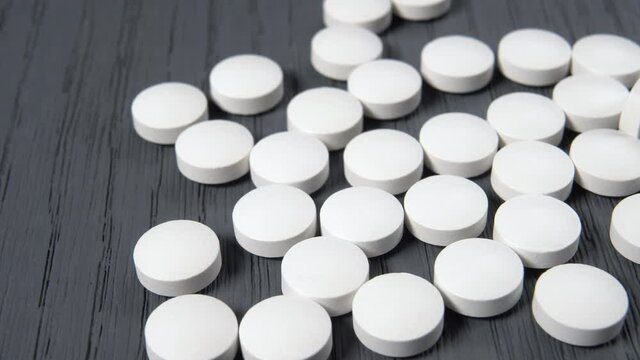 White round pills on a wooden grunge surface. The idea of research and testing a cure for the coronavirus pandemic, COVID-19