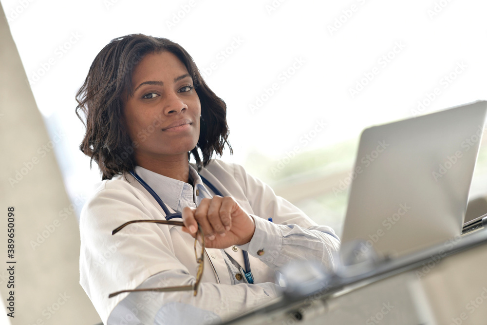 Wall mural woman doctor working in office with laptop computer