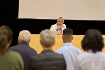 Doctor giving conference in convention center, audience in rear view