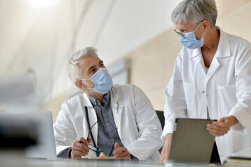 Medical people working together during pandemic, registering on tablet