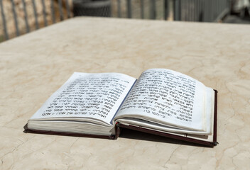 Fototapeta premium The open holy book of Jews with the text of prayers in Hebrew - Tehelim, lies on a table near the Western Wall in the old city. of Jerusalem in Israel