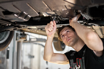 male mechanic is working on a vehicle in a car service, alone in modern clean workshop