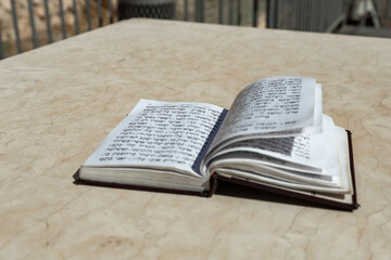 Obraz premium The open holy book of Jews with the text of prayers in Hebrew - Tehelim, lies on a table near the Western Wall in the old city. of Jerusalem in Israel