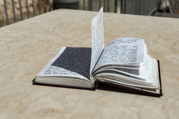 Fototapeta premium The open holy book of Jews with the text of prayers in Hebrew - Tehelim, lies on a table near the Western Wall in the old city. of Jerusalem in Israel
