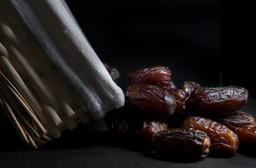 still life, chiaroscuro, renaissance or baroque style, group of dates fruit besides a basket and on a wooden table, close up image or macro photography