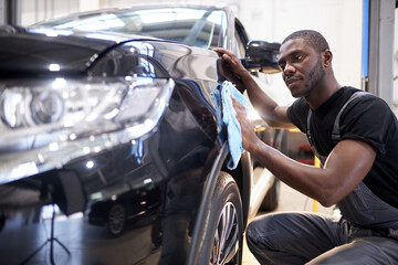repairing in action. hardworking guy employee in uniform works in the automobile salon, confident...