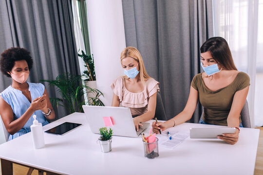 Female business colleagues with face masks working in the office - Powered by Adobe