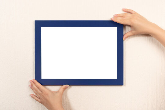 mockup diploma. woman hanging blue photo frame mockup on wall. White frame mockup. horizontal