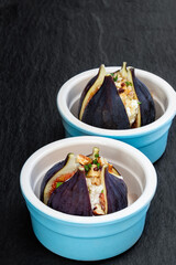 Figs with goat cheese and walnuts with honey on black stone background